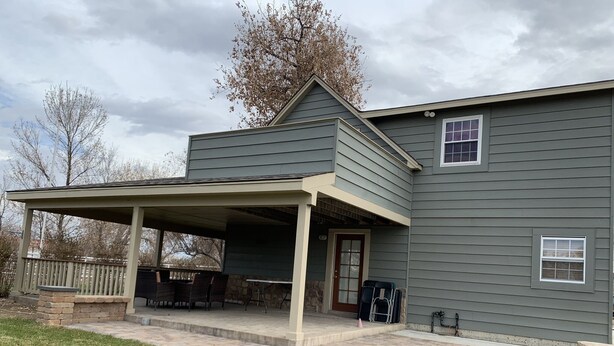 Une maison à deux étages dotée d’un patio couvert.