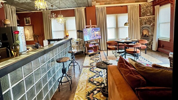 Een ruime woonkamer met een bar, een open haard en een groot vloerkleed.