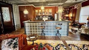 Een gezellige woonkamer met een bar in het midden, een open haard en een boekenkast vol boeken.
