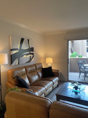 A living room with a leather sofa, a coffee table, and a large abstract painting on the wall.