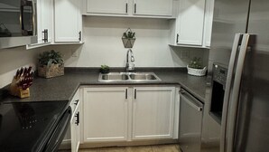 Una cucina moderna con mobili bianchi, un frigorifero in acciaio inossidabile e un lucernario.