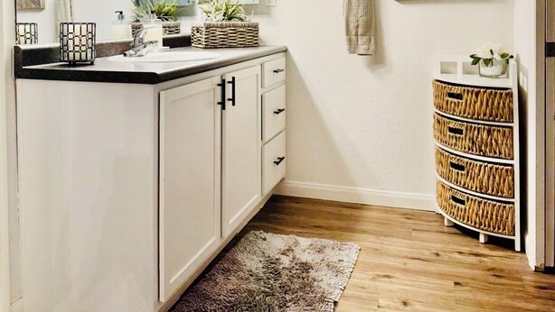 Un bagno moderno con un mobile lavabo bianco, uno specchio grande e un elemento decorativo a parete.