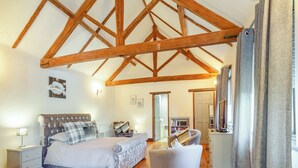 A bedroom with a large bed, a chair, a nightstand, a dresser, and a bookshelf. - 1 bedroom accommodation in Foulsham, near Reepham (Foulsham, near Reepham)