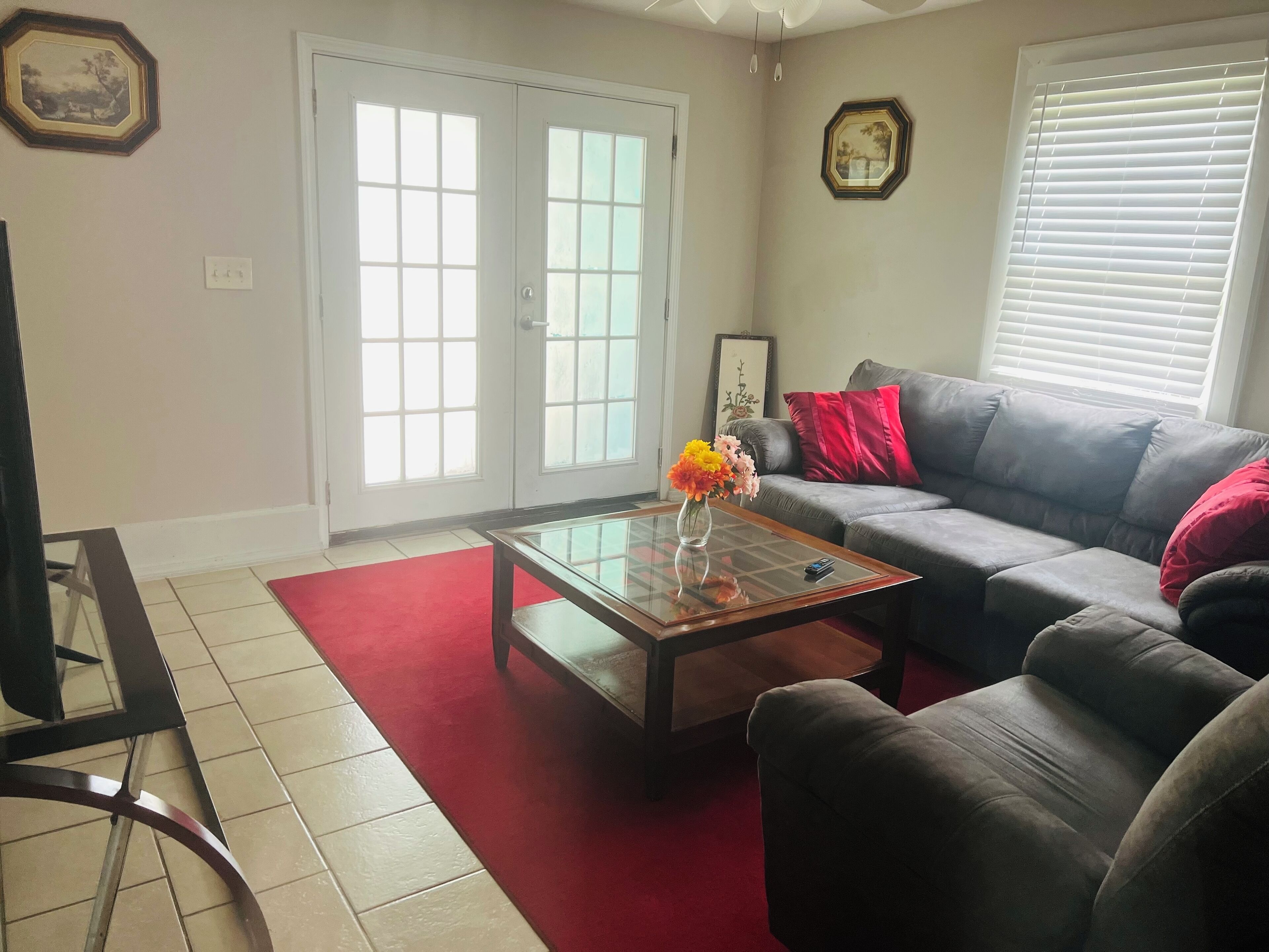 A living room with a sofa, a coffee table with a vase of flowers, and a red rug.
