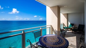 A balcony with a view of the ocean, a tiled table, and two chairs. - The CLIFF - 4th-floor Luxury Condo on the Beach - Luxury Beachfront Resort  (Cupecoy)