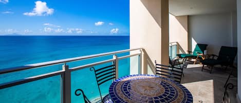Uma varanda com vista para o oceano, uma mesa de azulejos e duas cadeiras.