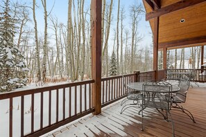 Guests can enjoy a peaceful winter retreat on the deck, surrounded by tall trees.