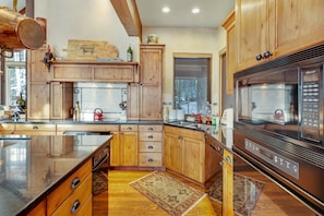 Kitchen features a central island, wooden cabinetry, and stainless steel appliances, including a refrigerator, microwave, and dishwasher.