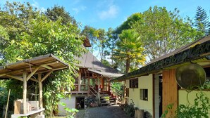A rustic wooden house with a covered porch and a gravel pathway leading to the entrance. - Hosteria La Roulotte Mindo (Mindo)