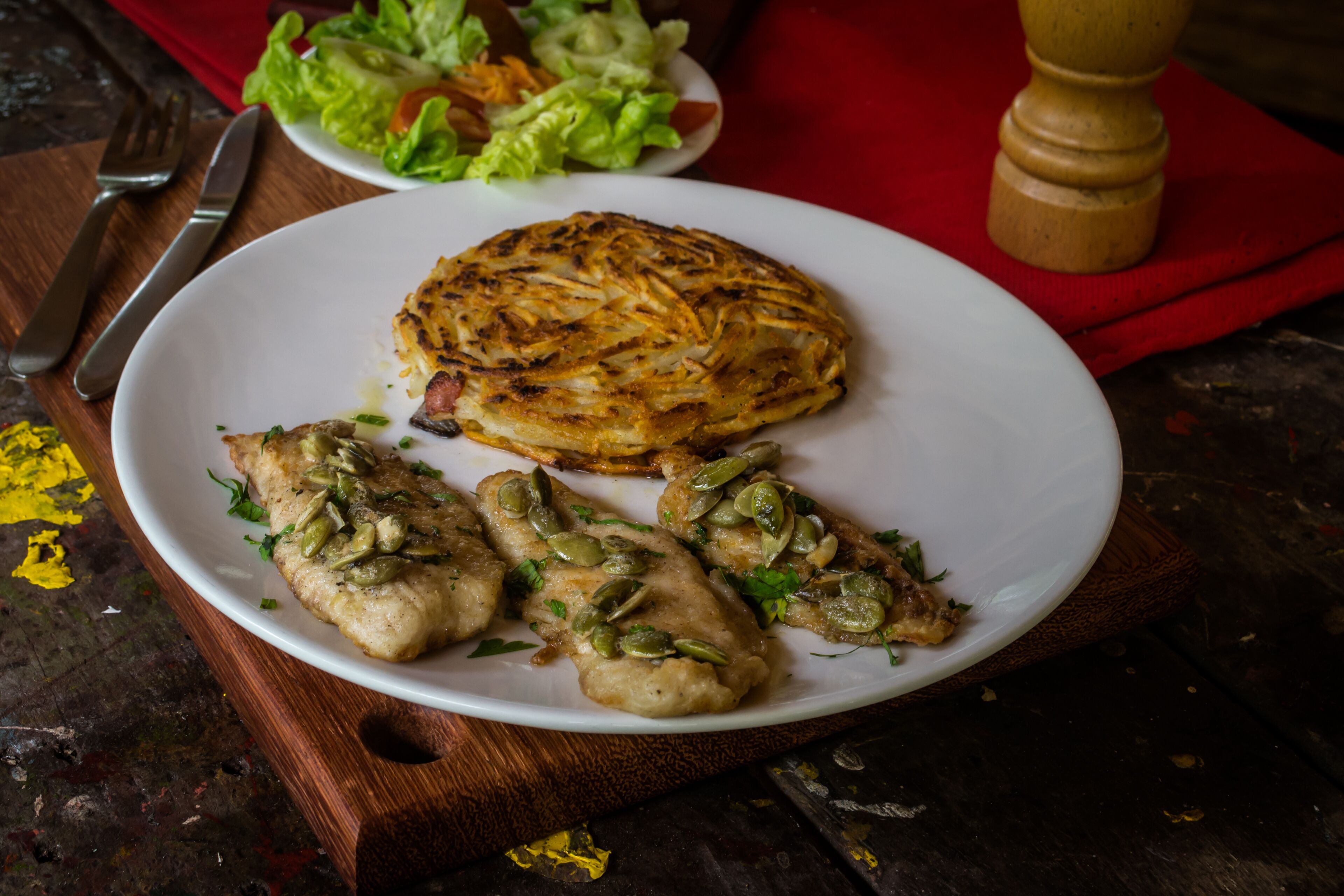 A plate with food, a fork, and a knife on a wooden table.