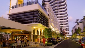 Un hôtel moderne à la façade incurvée, doté d’une terrasse et offrant une vue sur la rue.