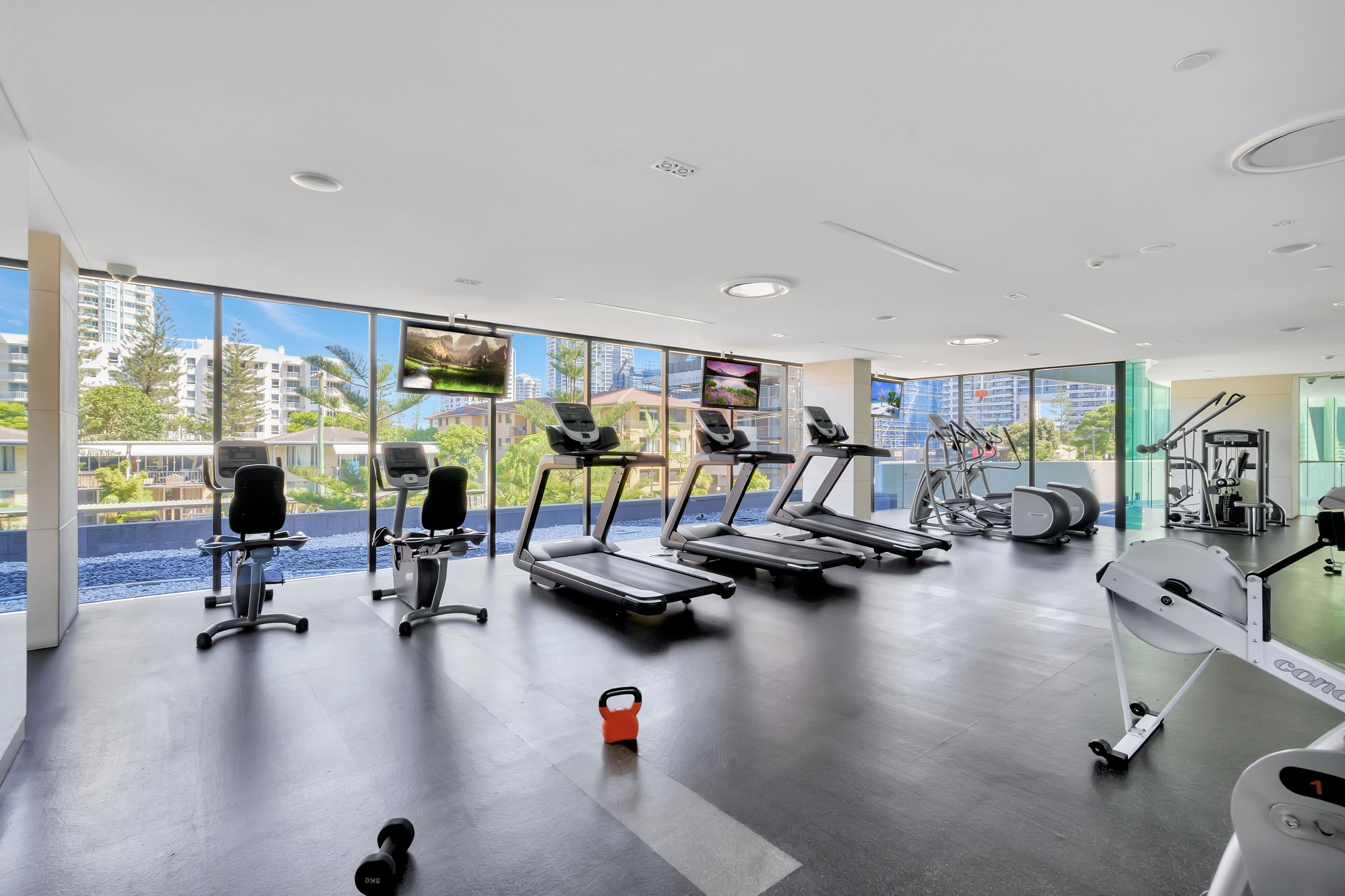 A modern gym with treadmills, stationary bikes, and weight machines.