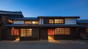 A traditional Japanese building with a wooden exterior, two visible windows with sliding doors, and a tiled roof.