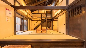 A traditional Japanese room with tatami flooring, a wooden staircase, and sliding doors.