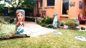 A courtyard with mosaic sculptures, a brick building, and a bench. - Stylish Comfortable Central Artists Home (Glen Waverley)