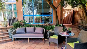 A patio with a wicker sofa, two wicker chairs, a small round table, and a potted plant. - Stylish Comfortable Central Artists Home (Glen Waverley)