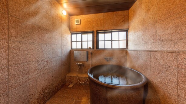 Un hammam doté d’une grande baignoire ronde en métal, d’une petite fenêtre et d’un système de ventilation fixé au mur.