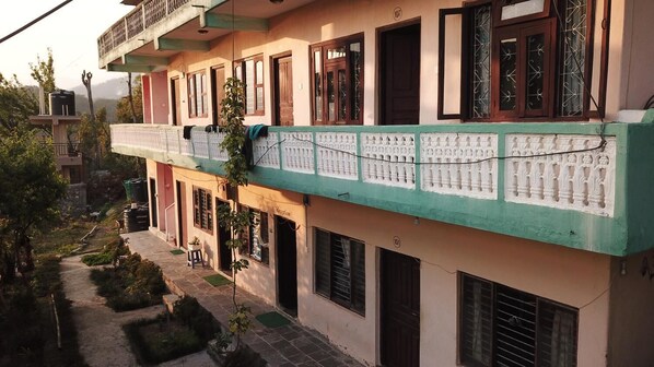 Un edificio de varios pisos con fachada verde y beige, múltiples ventanas y una recepción visible.