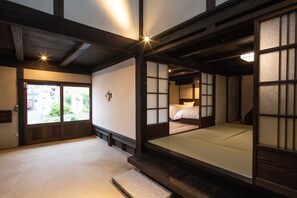 A traditional Japanese-style room with tatami flooring, sliding doors, and a low wooden bed. - SenzanAn Kajiyamachi 301 (Yuasa)