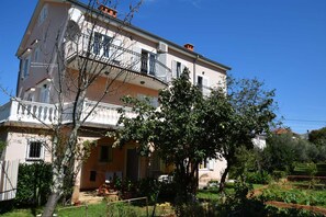 A multi-story building with balconies, a garden, and a clear sky. - Apartment Jelka 1 on the ground floor (Njivice)