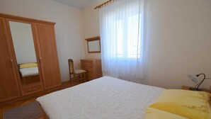 A bedroom with a bed, a wooden wardrobe, a chair, a dresser, and a window with sheer curtains. - Apartment Jelka 3 on the first floor (Njivice)