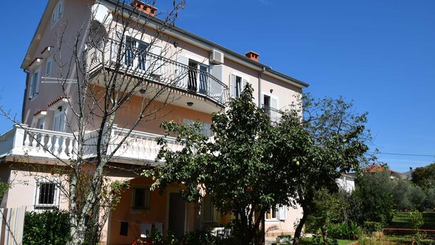 A multi-story building with balconies, a garden, and a clear sky. - Apartment Jelka 3 on the first floor (Njivice)