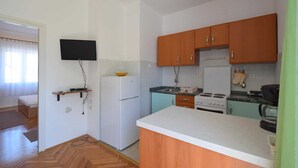 A compact kitchen with wooden cabinets, a white refrigerator, a stove, and a sink. - Apartment Jelka 3 on the first floor (Njivice)