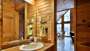 Un baño rústico en una cabaña de madera, con lavamanos, espejo y perchero para toallas.