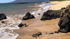 A beach with clear blue water, rocky outcrops, and a mountain in the background. - PICTURESQUE OCEAN VIEW CONDO - LAST MINUTE DEAL!  BEAUTIFUL WAILEA AT ELUA 2002 (Kihei)