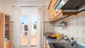 A kitchen with a sliding glass door leading to a balcony, a sink with fruit and drinks, and patterned tiles. - Rural retreat in the heart of nature: enjoy tranquility and privacy (Pollença)