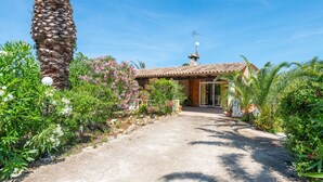 A house with a tiled roof, a stone chimney, and a garden with various plants and flowers. - Rural retreat in the heart of nature: enjoy tranquility and privacy (Pollença)