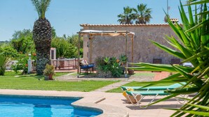 A swimming pool with lounge chairs, a stone wall, and a pergola. - Rural retreat in the heart of nature: enjoy tranquility and privacy (Pollença)