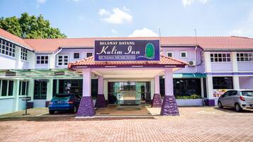 A hotel entrance with a sign reading "Kulim Inn" and a car parked in front.