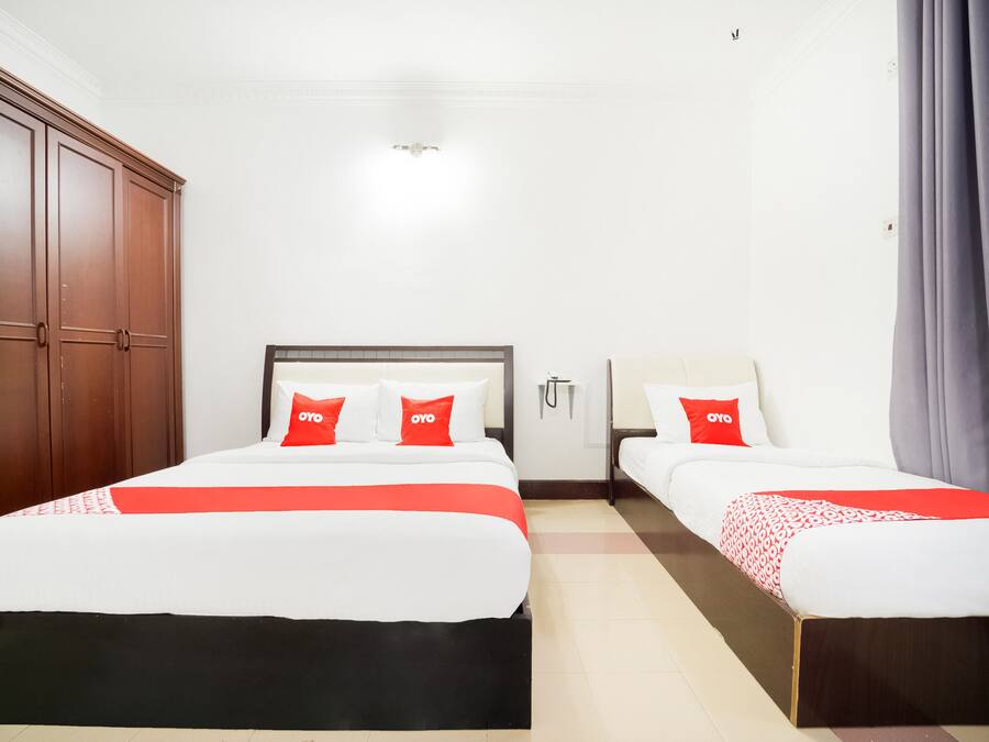A hotel room with two beds, a wardrobe, and a bathroom.