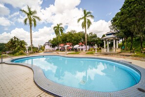 A swimming pool with tiled edges, surrounded by palm trees and a gazebo. - Hotel O Kulim Inn (Kulim)