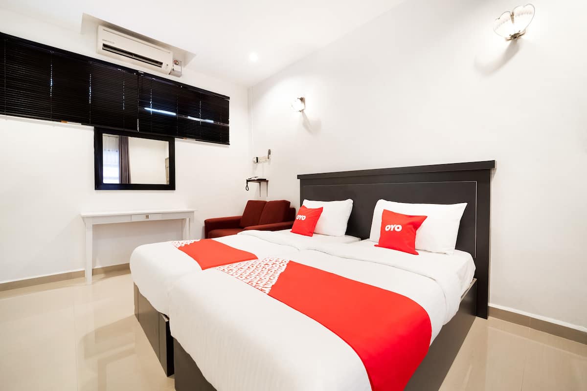Habitació d'hotel amb un llit gran, una taula de treball, una cadira i un aire condicionat fixat a la paret.