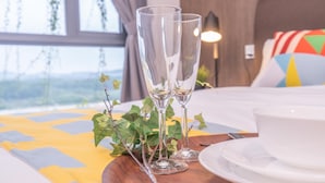 A neatly arranged table with two clear glasses, a white bowl, and a plate, set against a window with a view of greenery. - OYO Home 89312 Fantastic 1 Bedroom Starview (Gelang Patah)