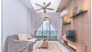 A modern living room with a sofa, coffee table, TV, and a ceiling fan. - OYO Home 89312 Fantastic 1 Bedroom Starview (Gelang Patah)