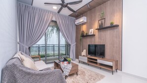 A modern living room with a sofa, coffee table, TV, and a balcony view. - OYO Home 89312 Fantastic 1 Bedroom Starview (Gelang Patah)
