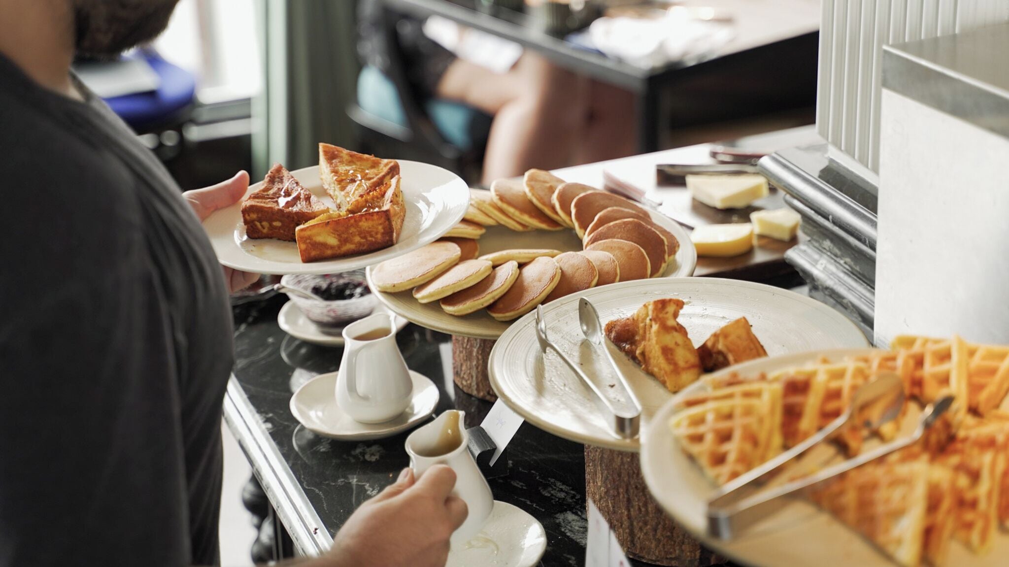 Un bufé con diferentes opciones para el desayuno, como panqueques, gofres y una rebanada de tostada.