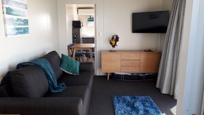Un salon avec un canapé, un téléviseur, un meuble en bois et un tapis bleu.
