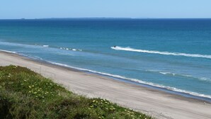 Une plage offrant une vue dégagée sur l’océan et sur la côte lointaine.