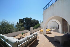 Relax on the patio surrounded by lush trees, with a sofa set, table, and chair.