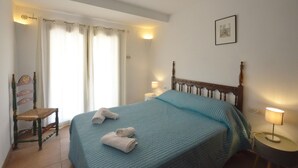 Ein Schlafzimmer mit einem Bett, einem Sessel, einem Nachttisch, einer Lampe und einem Bild an der Wand.