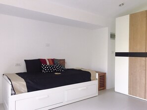 A bedroom with a bed, a wardrobe, and a small wooden stool.