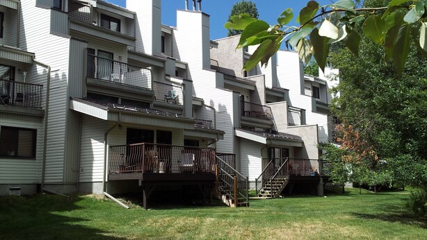 Un immeuble résidentiel à plusieurs étages, doté de balcons et d’un petit jardin devant.