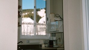 Une petite cuisine avec une fenêtre, un four à micro-ondes et une machine à café.