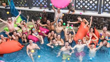 A group of people in a swimming pool with inflatable toys and a slide.