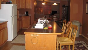 A kitchen with wooden cabinets, a refrigerator, a sink, and a dining area with chairs and a table.