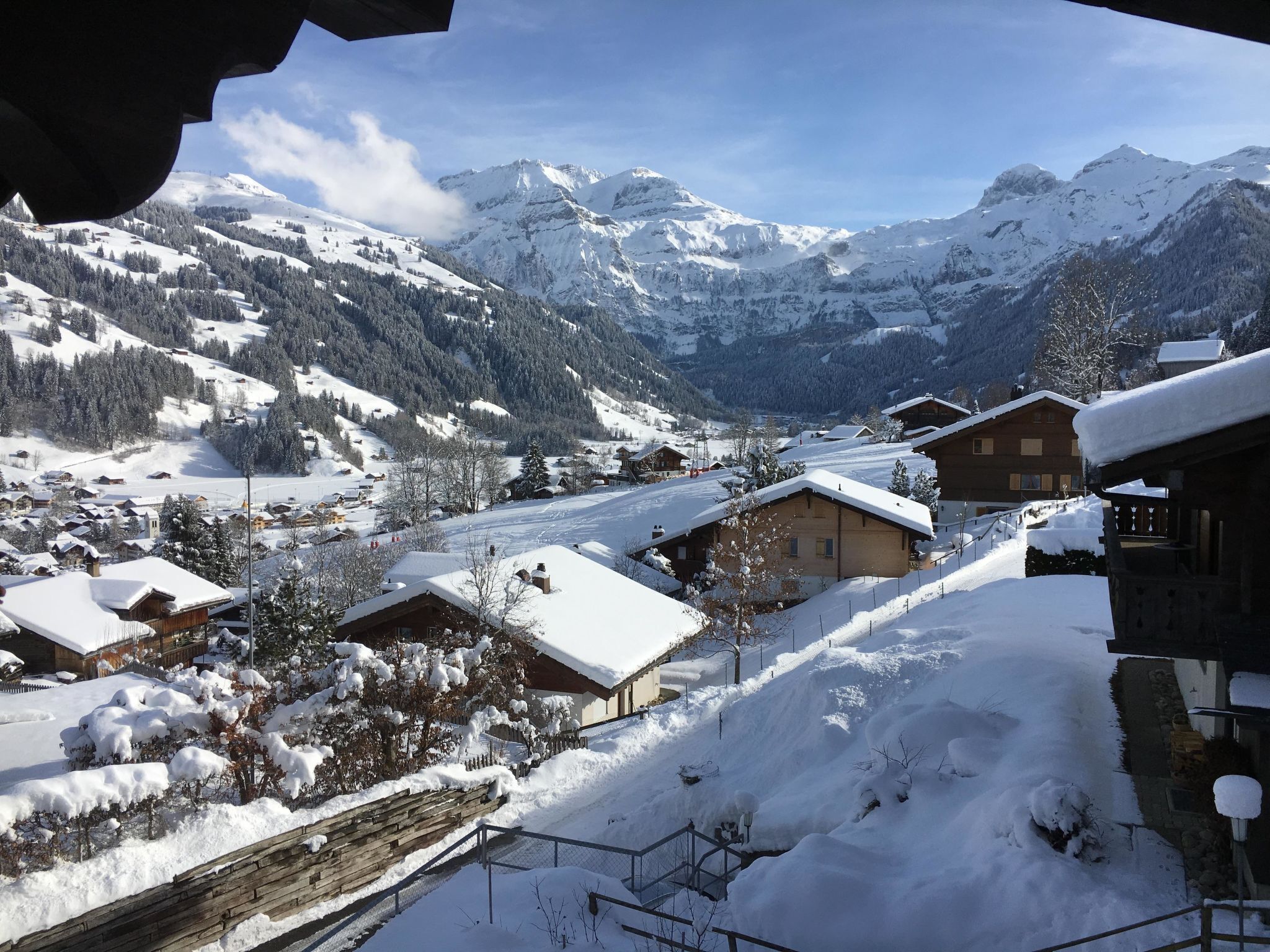 A snow-covered mountain village with wooden houses and a clear view of the surrounding peaks.